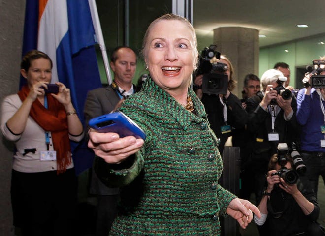 In this Dec. 8, 2011, file photo, then-U.S. Secretary of State Hillary Rodham Clinton hands off her mobile phone after arriving to meet with Dutch Foreign Minister Uri Rosenthal at the Ministry of Foreign Affairs in The Hague, Netherlands.