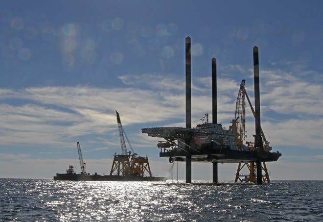 Specialized barge cranes hoist tower bases onto steel "jacket" foundations off Block Island on Nov. 9, 2015, as Deepwater Wind progressed toward this summer's construction: stacking the towers onto the bases and the turbines onto the towers. The Providence Journal/Steve Szydlowski.