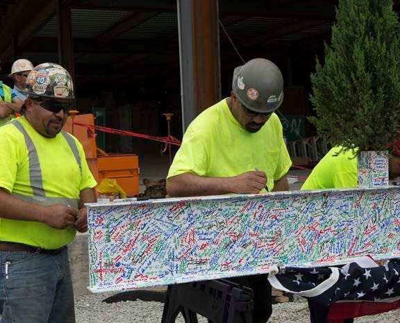 Octavio Castillo and Rover Pineda sign their names to a an I-beam Thursday at CarolinaEast’s ‘topping out’ ceremony. The ceremony celebrated the placing of the decorated beam at the top of the future Women’s Center and emergency department expansion.