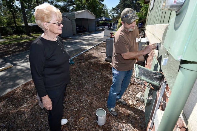 Vermillion (left) watches as Brandon Moore paints some trim. The joint volunteer effort was organized after Vermillion inquired about an audit program to make the home more energy efficient about two years ago.
