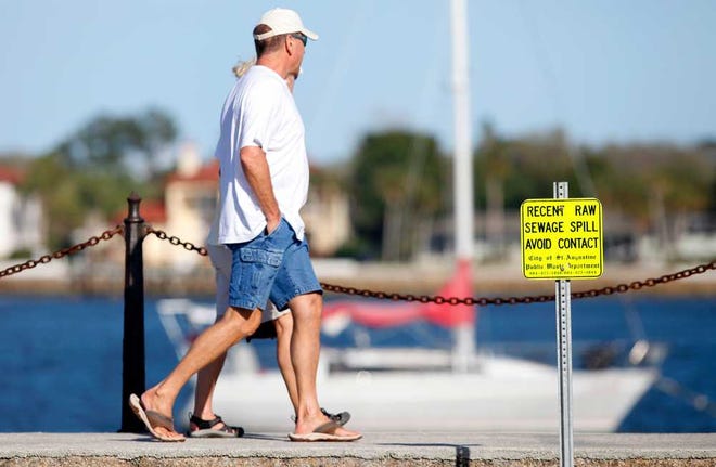 DARON.DEAN@STAUGUSTINE.COM A couple walks south, from the Castillo De San Marcos, along St. Augustine's bay front near a sign waring of a recent raw sewage spill in March of 2015.