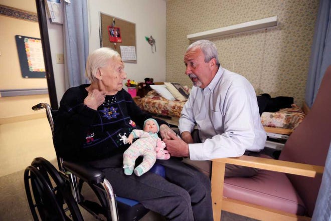 Glen Hotchkiss talks to his 93-year-old mother, Phyllis, at her nursing home in Adrian, Mich. Phyllis, who has dementia and must use a wheelchair, was involuntarily discharged from her nursing home this year to one 35 minutes away from her family. Her son is able to visit her far less often now.