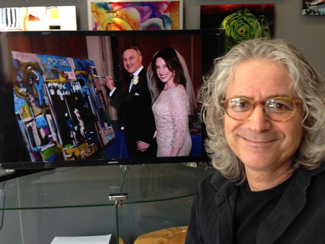 Roni Golan, owner of State of the Art, sits in his downtown Rockford gallery on Tuesday, May 3, 2016, next to a photo showing Larry and Lisa Pearlman of Roscoe with the painting he created at their wedding reception. GEORGETTE BRAUN/STAFF PHOTOGRAPHER/RRSTAR.COM