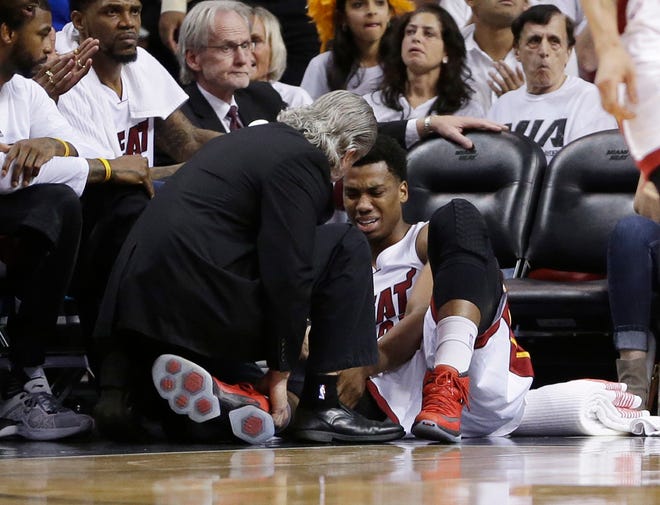 Miami Heat center Hassan Whiteside (21) is attended by a team member after he was injured during the first half of Game 3 of an NBA second-round playoff basketball series against the Toronto Raptors, Saturday, May 7, 2016, in Miami.