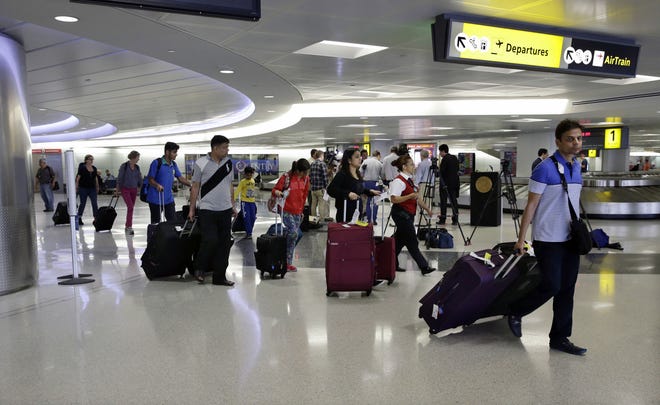 Passengers pull their luggage at Newark Liberty Airport Monday, June 15, 2015, in Newark, N.J. Earlier Sen. Bob Menendez, D-NJ, addressed new rules proposed to reduce the size of airline travelers' carry-on bags. Menendez says the new rule would force many travelers to pay for checked baggage. He says statistics from the federal Department of Transportation show the 27 U.S.-based airlines made $3.5 billion in baggage fees last year. (AP Photo/Mel Evans)
