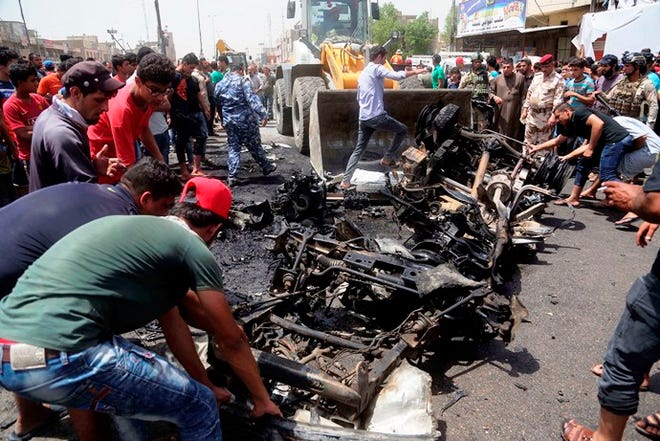 Civilians help a municipality bulldozer clean up after a car bomb explosion on Wednesday at a crowded outdoor market in a predominantly Shiite neighborhood of Baghdad.