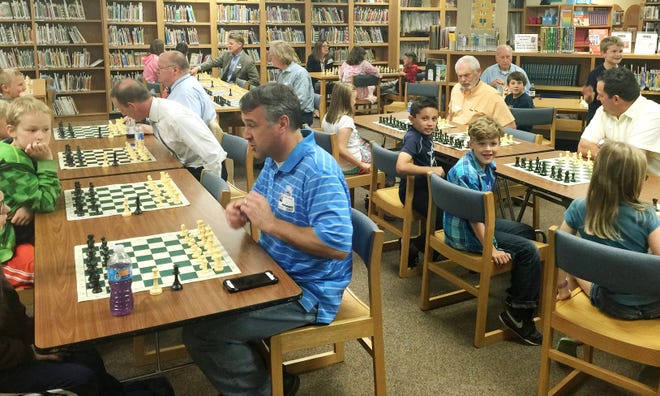 Edmond Rotary Club members play chess with the award-winning team at Ida Freeman Elementary School. Among participants are Edmond Mayor Charles Lamb, right of center (wearing yellow shirt), who ponders his next move. [Photo provided]