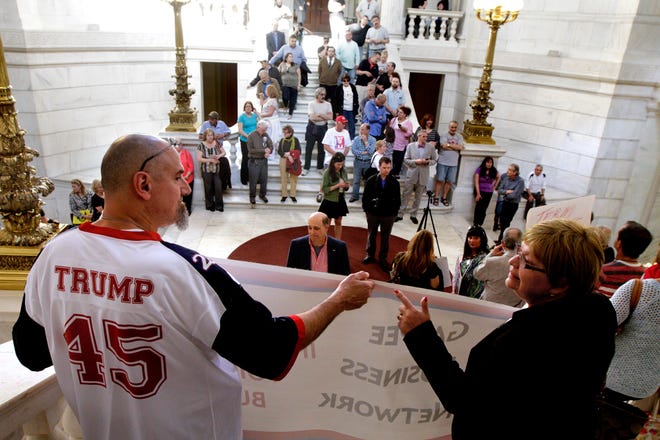 Paul Walker and Valeria Varrecchione, both of Smithfield, chat while holding a banner as people gather for a rally at the State House Wednesday afternoon. The Providence Journal / Kris Craig