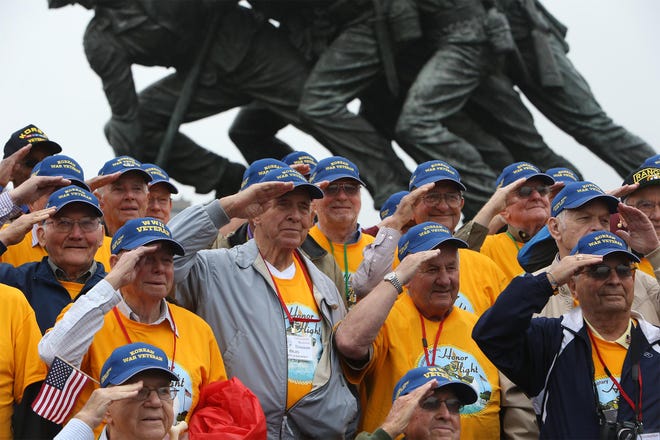 Veterans salute as photographs are made at the Marine Corps War Memorial during the seventh Tuscaloosa Rotary Honor Flight to Washington, D.C. on Wednesday. The memorial depicts the raising of the American Flag at Iwo Jima uring World War II.