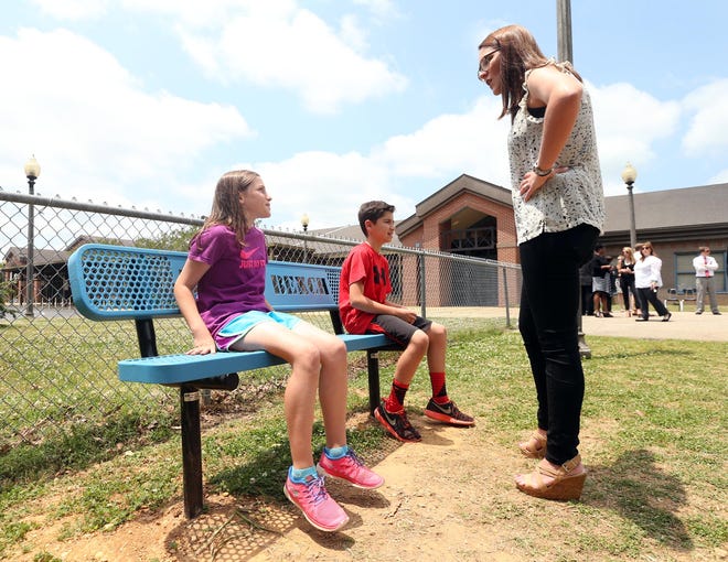 Brandt LaPish, a member of Leadership Tuscaloosa, explains the purpose of a "Buddy Bench" to Kathryn Case, 11, and Ben Willoughby, 11, at Rock Quarry Elementary school Wednesday. Leadership Tuscaloosa raised funds to have 32 "Buddy Benches" installed at all schools in the Tuscaloosa city and county school systems this year.