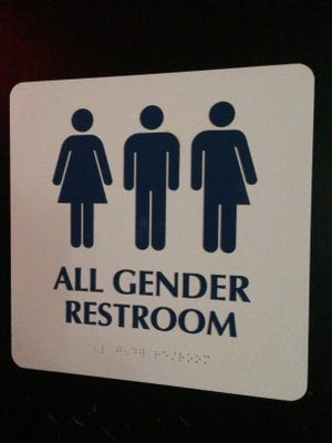 This May 11, 2014. photo shows an 'All Gender Restroom' sign outside a bathroom in a bar in Washington. Confrontations have flared across the country over whether to protect or curtail the right of transgender people to use public restrooms in accordance with their gender identity. (AP Photo)