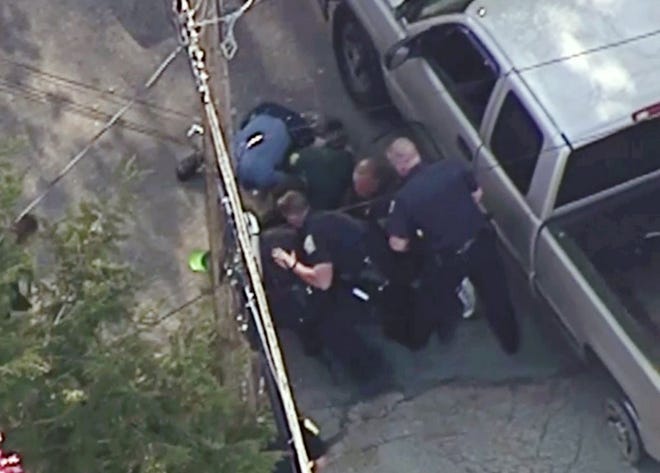 This aerial image made from a helicopter video provided by WHDH shows several officers pummeling Richard Simone, who had exited his vehicle and kneeled on the ground after a high-speed police pursuit, in Nashua, N.H., Wednesday, May 11, 2016.