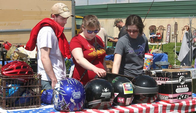 Josh Niles (left) shops for motorcycle helmets with his friends Kristina Bonk and Amanda Busby at the May 2015 semi-annual Pec Thing Antique & Flea Market at the Winnebago County Fairgrounds in Pecatonica. RRSTAR.COM FILE PHOTO