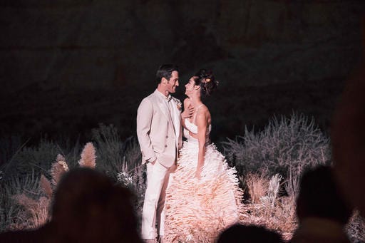 Photo provided by Izak Rappaport, Bride Andi Potamkin wed Jordan Blackmore in an outdoor ceremony at the Canyon Point, Utah, resort Amangiri. Potamkin, now Potamkin Blackmore, wore a custom skirt and bra top designed by Maurizio Galante. More brides like Potamkin Blackmore are choosing to express their individuality in non-traditional bridal looks such as midriff-baring two-piece outfits, tuxedo-inspired suits and jumpsuits in white or blush tones. (Izak Rappaport via AP)