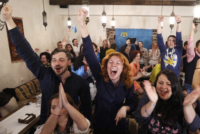 People celebrate while watching TV as Jamala of Ukraine wins the final of the Eurovision Song Contest in Stockholm, in a restaurant in Kiev, Ukraine, Sunday, May 15, 2016. (AP Photo/Sergei Chuzavkov)