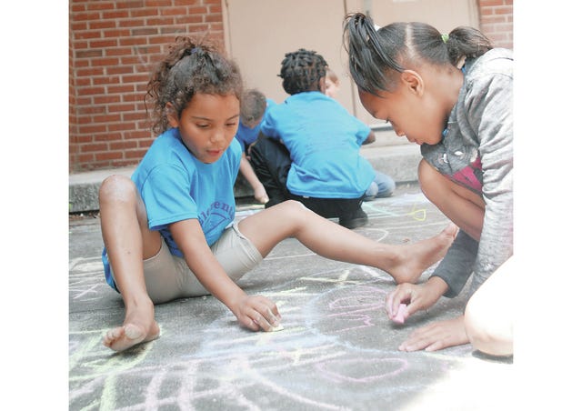 Laney Richardson, 8, and Kemoria Symlar, 7, add ‘X’s and ‘O’s to the sidewalk art that others have drawn in a different kind of tic-tac-toe game Monday afternoon in front of McDowell Elementary School following the annual field day events. The younger students were enjoying the sunny day, jumping in the bounce houses and drawing on the sidewalks with chalk. (Staff photo by Susan W. Thurman)