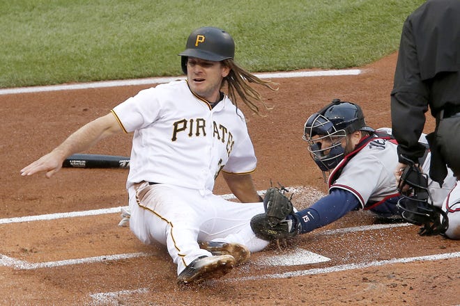 Pirates first baseman John Jaso (28) knocks the ball out of the glove of Braves catcher A.J. Pierzynski to score on a fielder's choice by in the first inning of Tuesday's game in Pittsburgh. The Pirates won 12-9.