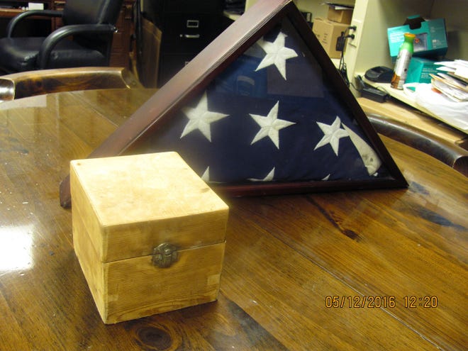 This May 5 photo shows a box and a flag sitting on a table after a south Alabama police chief says a power line crew found the abandoned small pine box with a rusted lock and an American flag.