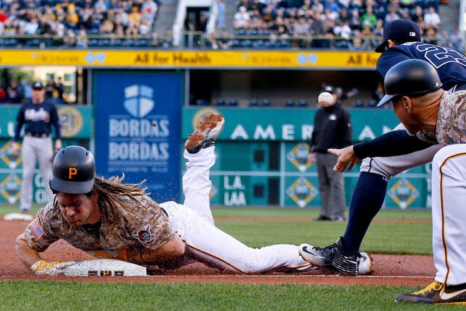 Pittsburgh's John Jaso slides into third base with a triple as the ball gets away from Atlanta's Chase d'Arnaud (right) in the second inning Thursday. Jaso had three hits as the Pirates sent the Braves to their 30th loss of the season.