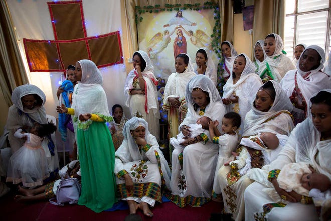 Eritrean Christian Orthodox migrant women hold their babies during a baptism ceremony at a makeshift church in Tel Aviv, Israel.