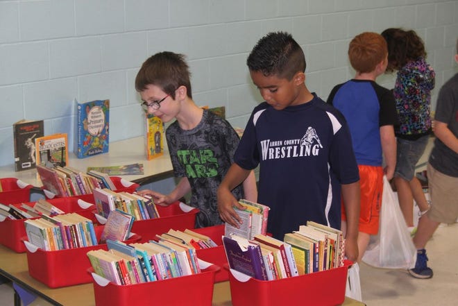 Harding Primary second graders Garret Wensel (left) and Efren
Huerta flip through several containers to find the right book Friday
morning during Harding's annual Book Shower.