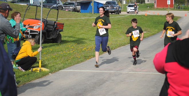 Participants in the Will Carleton 5K run are cheered on as they cross the finish line. COURTESY PHOTO