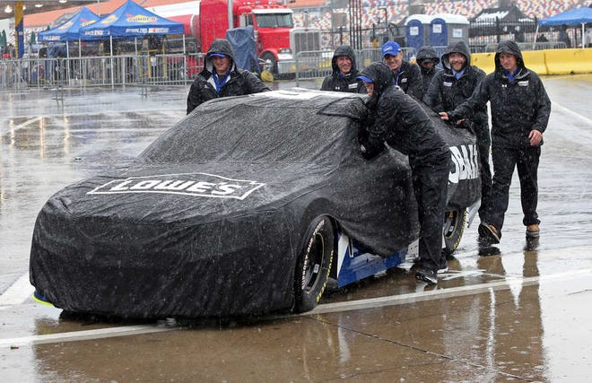 Crew members push driver Jimmie Johnson's car through the garage area at Charlotte Motor Speedway in Concord, N.C., Friday, May 20, 2016 before the scheduled start of the NASCAR Sprint Showdown auto race later today. Activities at the track have been delayed because of rain in the area. (AP Photo/Bob Jordan)
