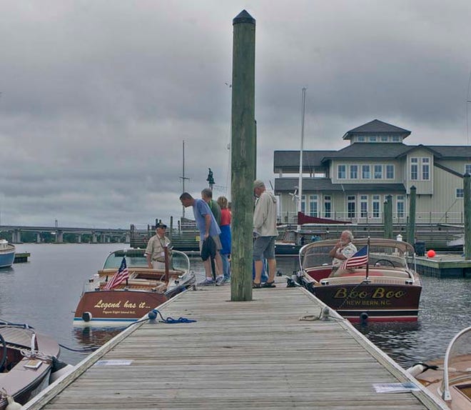 Attendees of the Antique and Classic Boat Show look over several wooden boats at dock at the Galley Store Marina Saturday morning.
