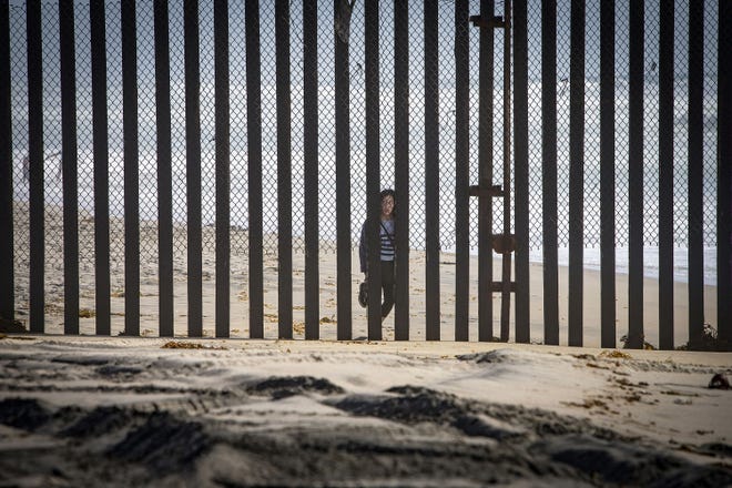 A person from Tijuana in Mexico peers through the border fence April 14 at the Border Field State Park in Imperial Beach, Calif.