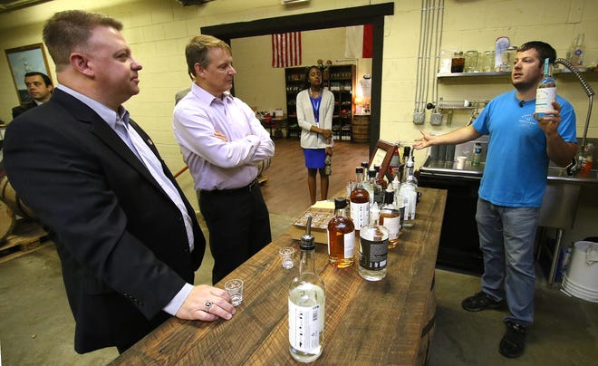 Reps. Jason Saine, left, and Mike Hagar listen as owner Robbie Delaney talks about one of his company's flavors of Carolina Rum during a tour Friday morning at Muddy River Distillery in Belmont. MIKE HENSDILL/THE GAZETTE