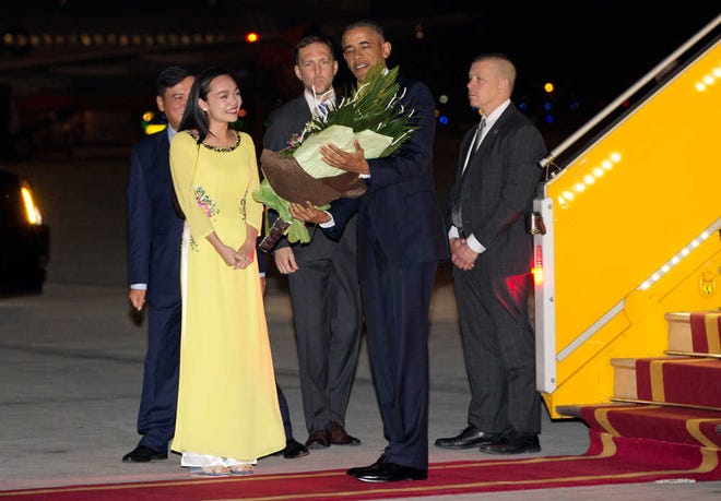 U.S. President Barack Obama is given flowers by Linh Tran, the ceremonial flower girl, as he arrives on Air Force One at Noi Bai International Airport in Hanoi, Vietnam, Sunday, May 22, 2016. The president is on a weeklong trip to Asia as part of his effort to pay more attention to the region and boost economic and security cooperation. (AP Photo/Carolyn Kaster)