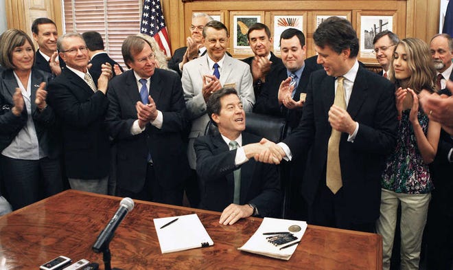 Kansas Governor Sam Brownback shakes hands with Lt. Gov. Jeff Colyer, after signing into law one of the largest tax cut bills in Kansas history. The signing took place in the governors statehouse cermonial office Tuesday May 22, 2012, surrounded by small business owners and state legislators.