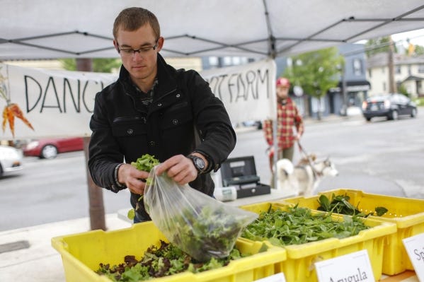 At the Dangling Carrot Farm booth, Seth Brunfield of Williamsport, Ohio, bags mixed greens for Clintonville Farmers' Market customers.