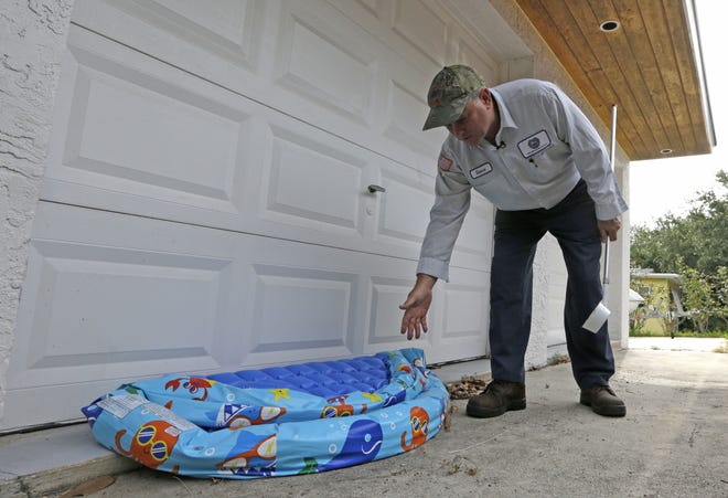 In this photo taken Thursday, May 12, 2016, Steve Noe, Martin County mosquito specialist, points to a beach inflatable where water can accumulate and become a breeding place for mosquitos, during an inspection outside a home in Rio, Fla. The dengue fever outbreak that infected 28 people in August and September of 2013 caught Florida's Atlantic coast by surprise. The mosquito-borne disease many associate with crowded, third-world conditions had spread among the pink plastic flamingoes in their modest suburban yards. (AP Photo/Alan Diaz)