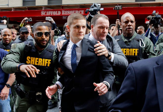 John Nero, center left, and Edward Nero, center right, brother and father of Officer Edward Nero, one of six Baltimore city police officers charged in connection to the death of Freddie Gray, are escorted out of a courthouse after Nero was acquitted of all charges in his trial in Baltimore, Monday, May 23, 2016. (AP Photo/Patrick Semansky)