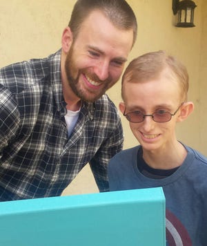 In this Monday, May 23, 2016, photo provided by Amy Wilcox, Captain America Chris Evans talks with Ryan Wilcox during a surprise visit with Wilcox at his home in El Cajon, Calif. The Avengers teamed up to lift the spirits of the teenage fan, Ryan Wilcox, a junior, who has been at home for months battling leukemia. (Amy Wilcox via AP)