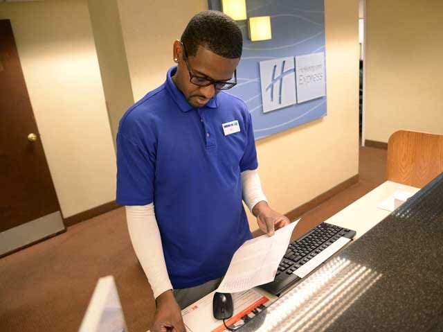 Cardiesse Veal, a guest service representative at the Holiday Inn Express in Kinston, prepares room keys for reservations, Tuesday. With the National Junior College Athletic Association baseball World Series in town, local business reap the economic benefits.