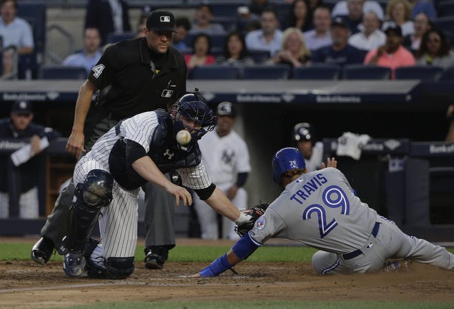 The bal pops out of Yankees catcher Brian McCann's glove as he attempts to put the tag on Toronto Blue Jays' Devon Travis during the fourth inning of the Yankees' 8-4 loss on Wednesday. Travis was safe on the play. Associated Press