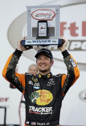 Martin Truex Jr. poses with the trophy in victory lane Thursday after winning the pole position for Sunday's Sprint Cup race at Charlotte Motor Speedway in Concord. (AP Photo/Chuck Burton)