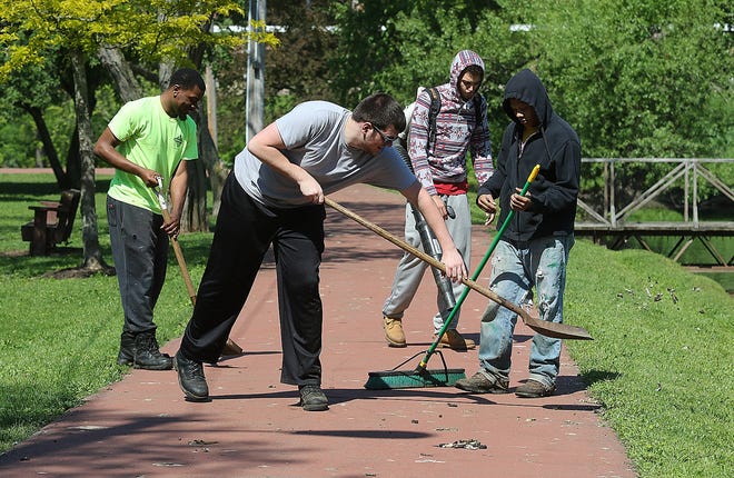 Massillon Parks and Recreation Department summer workers (from left) Damian Williams, Davis McCue, Jordan Stock and Alex Purnell, work to clean goose droppings off the walking path in Massillon's Resevoir Park. (IndeOnline.com / Kevin Whitlock)