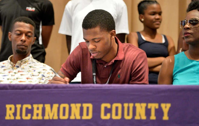 Former Richmond Academy star Britto Tutt is joined by his parents during his signing ceremony Friday. Tutt graduated from Richmond Academy in 2015 and spent last season at Ventura College in California. He will play at Arkansas.