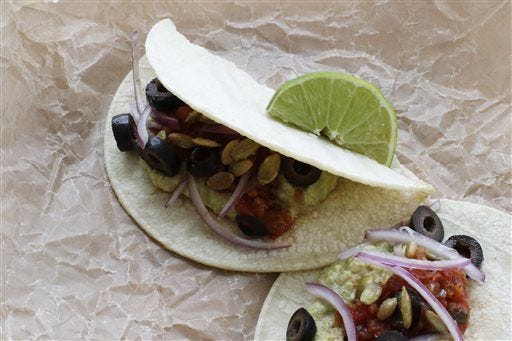 Refried edamame in a flour tortilla garnished with lime, toasted pumpkin seeds, olives and onions. For a lighter version of Mexican-styled refried beans, replace the pinto beans with edamame. (AP Photo/J.M.Hirsch)