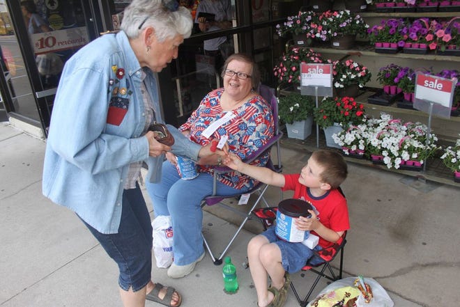 Penny Vaughn of Monmouth buys a poppy from Caleb Strange, 9, and his grandmother Liz Waller on Friday afternoon outside ShopKo.