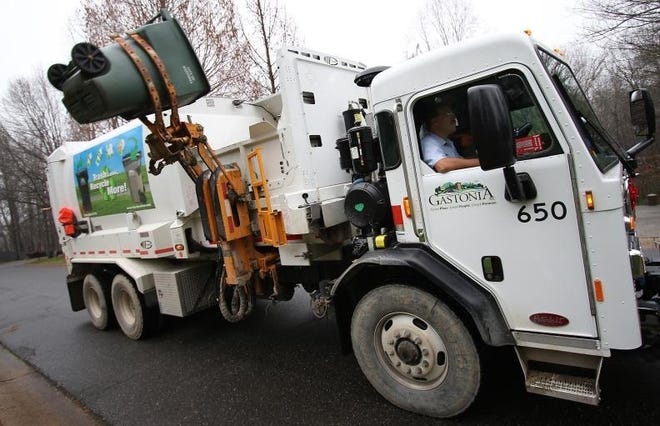 Gastonia solid waste workers empty a curbside garbage container. File photo