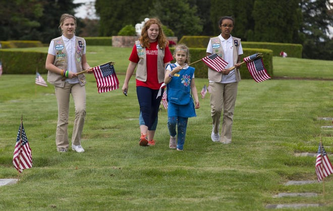 Girl Scouts from Troop 20337 volunteered on Thursday to place American flags at the graves of the servicemen and women buried at West Lawn Memorial Park. (Chris Pietsch/The Register-Guard)