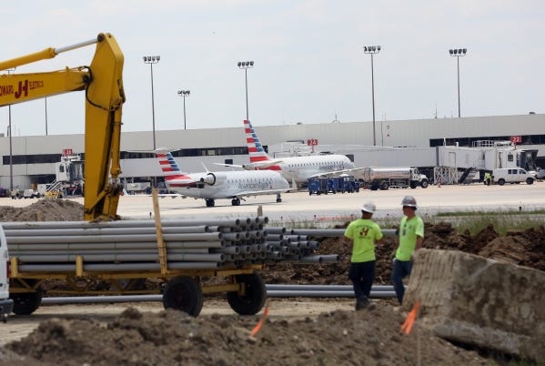 One of Port Columbus' two runways has been closed since April 4 for 180 days of heavy maintenance. As part of that work, pipes are delivered to workers while planes taxi nearby on Tuesday.