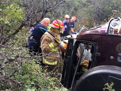 This photo provided by Kim Moore shows firefighters working to extricate a 50-year-old man from his crashed car on Mingus Mountain in Yavapai County, Arizona on Friday, May 27, 2016. Authorities say a man trapped in his crashed vehicle on a central Arizona mountain for three days was rescued thanks to a couple taking sightseeing photos. (Kim Moore via AP)