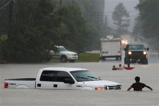 A man, foreground, checks to make sure everyone made it safely out of a truck that flooded when the three men in the background drove around a closed road barrier along Nichols Sawmill Road and lost control of the vehicle in rising flood water Friday, May 27, 2016 in Magnolia, Texas. (Michael Ciaglo/Houston Chronicle via AP) MANDATORY CREDIT