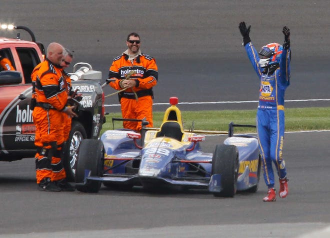 Alexander Rossi celebrates his Indianapolis 500 victory while workers attach a rope to his car so it can be towed back to Victory Lane. Rossi won even though he was running on fumes and completed the final lap at 179.784 mph.