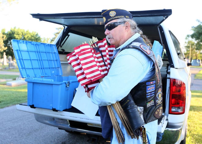 Dave Schoonover takes an armful of flags to place at Eastside Cemetery on Saturday morning.